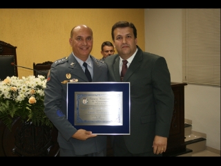 O capitão PM Eurico recebeu a placa comemorativa diretamente das mãos do então presidente da Câmara, Dr. José Renato Cunha Martinez (PTB). 